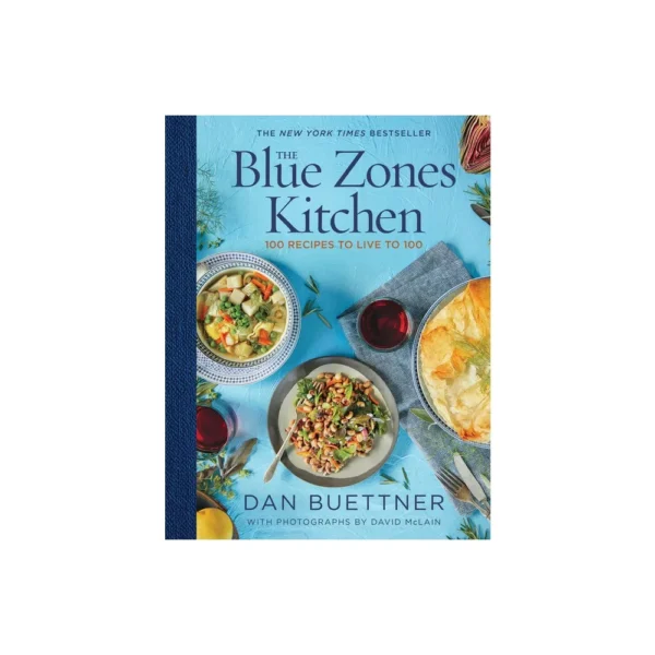 Blue The Blue Zones Kitchen book with 100 recipes to live to 100 written by Dan Buettner. Cover features a soup with peas, carrots and hearts of palm. Additionally has a salad with black eyed peas and a glass of red wine. Cover also has a pot pie.