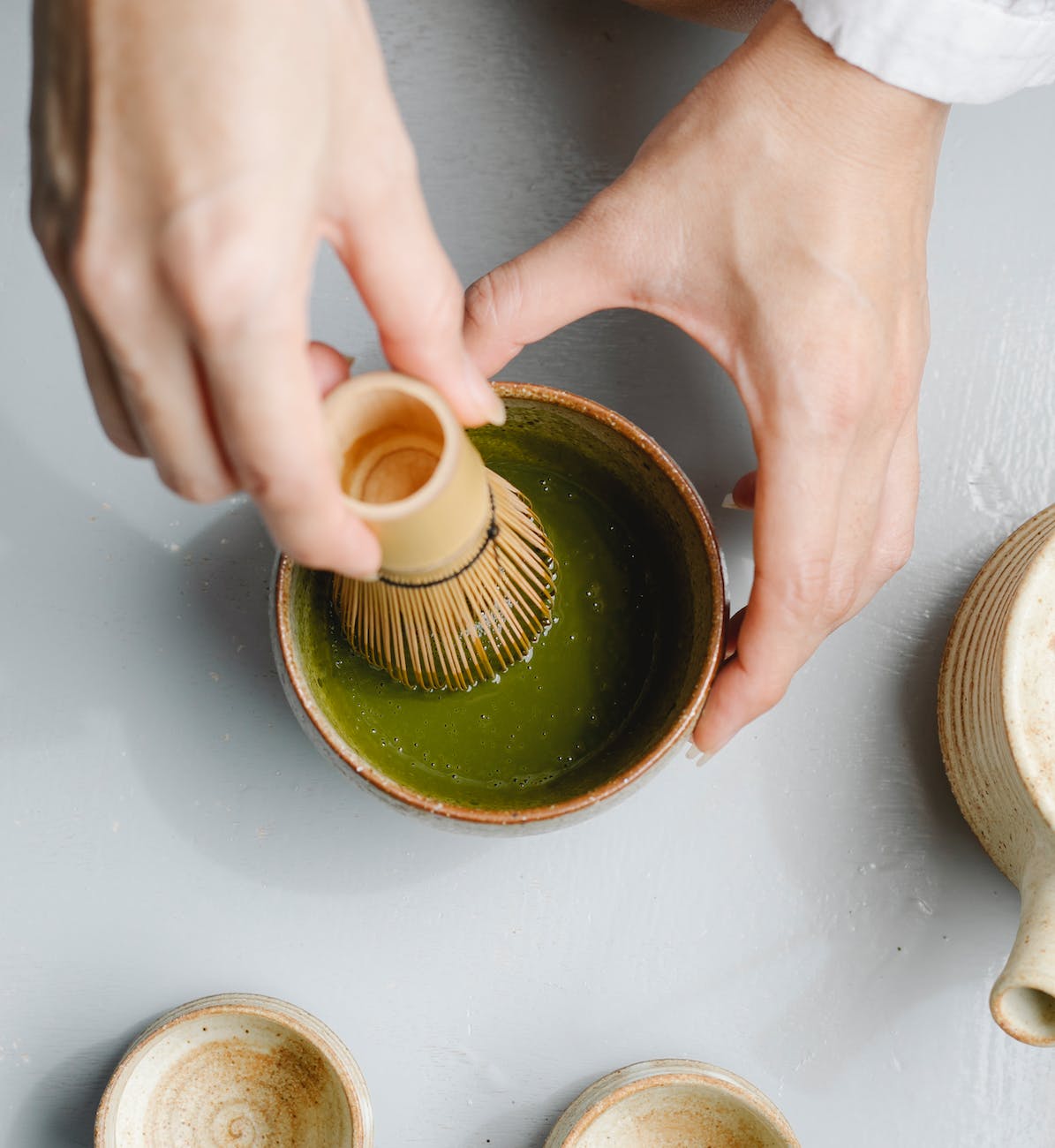 person preparing tea in bowl for tea ceremony