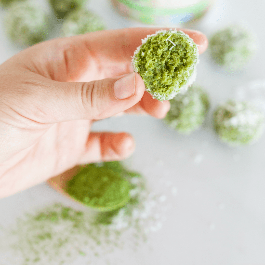 A hand holding a protein snack or energy ball made with green matcha