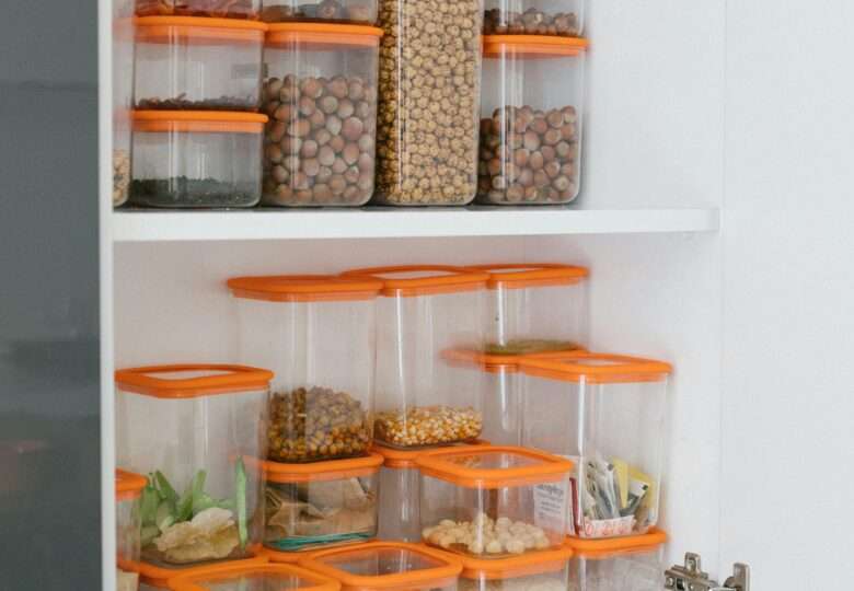 Clear food storage containers with orange filled with nuts, seeds, corn, pumpkin seeds, granola, Flour
